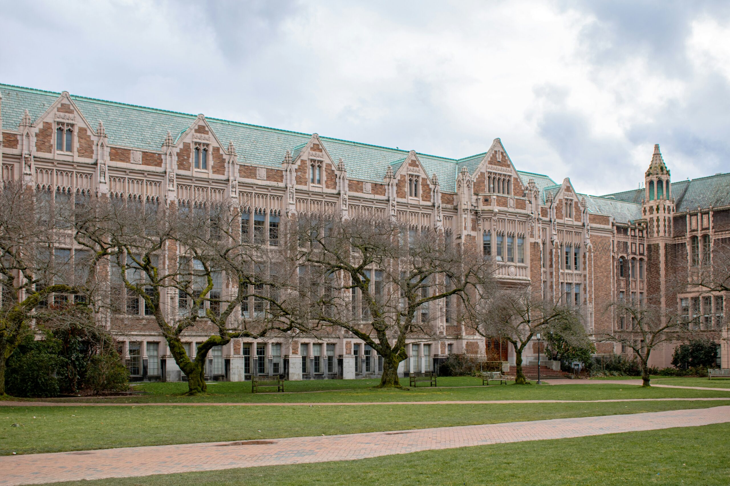 Campus building overlooking a lawn and tree-lined walkway